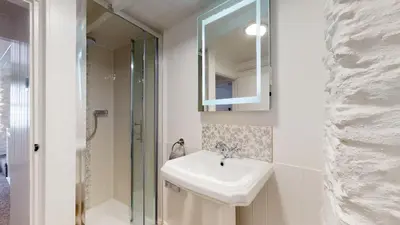 a white bathroom with a sink and a shower at Lobster Cove, Excellent location, Close to beach & coastal walks, Family run in Port Isaac