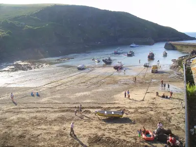 a group of people on a beach with boats in the water at Lobster Cove, Excellent location, Close to beach & coastal walks, Family run in Port Isaac