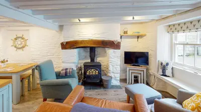 a living room with a stone fireplace and a tv at Lobster Cove, Excellent location, Close to beach & coastal walks, Family run in Port Isaac