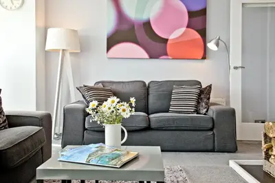 a living room with a couch and a table with flowers at Spindrift - Hot Tub - Free WiFi - Free Parking - Pet Friendly in Praa Sands