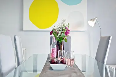 a glass table with a vase of flowers and a bowl of fruit at Spindrift - Hot Tub - Free WiFi - Free Parking - Pet Friendly in Praa Sands