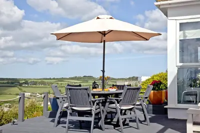 a table and chairs with an umbrella on a patio at Spindrift - Hot Tub - Free WiFi - Free Parking - Pet Friendly in Praa Sands