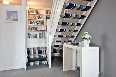 a room with a staircase with bookshelves at Spindrift - Hot Tub - Free WiFi - Free Parking - Pet Friendly in Praa Sands