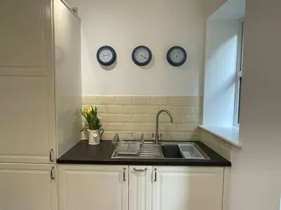 a kitchen with a sink and three clocks on the wall at Fabulous 2 Bed Cottage - Outstanding Sea Views in Mevagissey