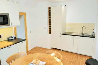 a kitchen with white cabinets and a wooden table at Fabulous 2 Bed Cottage - Outstanding Sea Views in Mevagissey