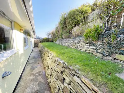 a stone retaining wall next to a house at Sunnybank, Port Isaac Bay Holidays in Port Isaac