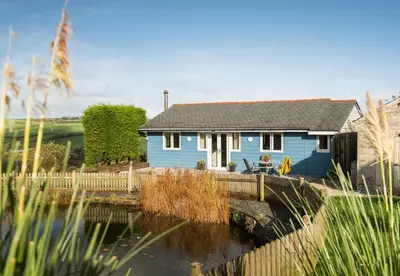 a blue house sitting next to a body of water at The Hut in Bodmin