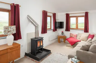 a living room with a fireplace and a couch at The Hut in Bodmin