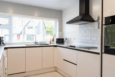 a kitchen with white cabinets and a large window at Finest Retreats - Tinners Rest in St Austell