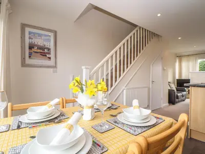 a dining room with a table with white dishes on it at 24 Atlantic Reach in Newquay