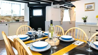 a dining room with a table with plates and wine glasses at Ta Mill Holiday Cottages & Lodges - Forge Cottage in Launceston