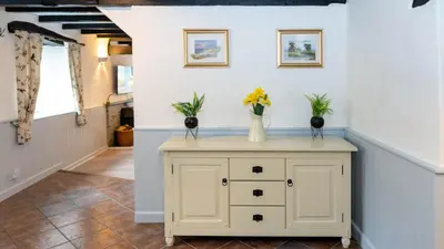 a hallway with a table with flowers in vases on it at Ta Mill Holiday Cottages & Lodges - Forge Cottage in Launceston