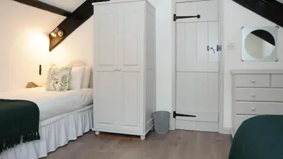 a bedroom with a large white cabinet next to a bed at Ta Mill Holiday Cottages & Lodges - Forge Cottage in Launceston
