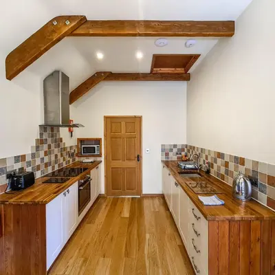 a kitchen with white cabinets and a wooden counter top at Ta Mill Cottages & Lodges - Olde Granary in Launceston