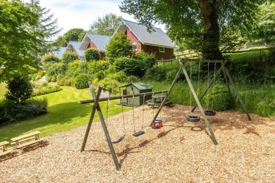a playground with a swing set in a yard at Ta Mill Cottages & Lodges - Olde Granary in Launceston