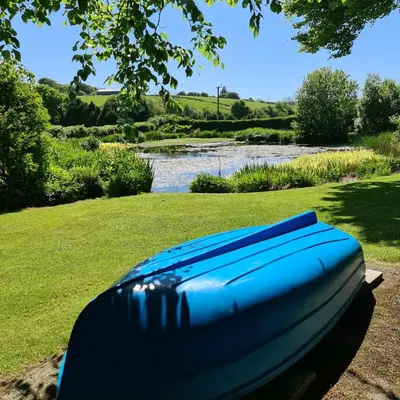 a blue boat sitting on the grass next to a river at Ta Mill Cottages & Lodges - Millers Cottage in Launceston