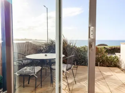 a glass door leading to a patio with a table and chairs at Flat 2 in Newquay
