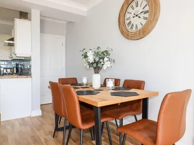 a dining room table with chairs and a clock on the wall at Flat 2 in Newquay