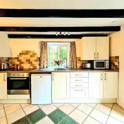 a kitchen with white cabinets and a sink and a window at Ta Mill Cottages & Lodges - Pump Cottage in Launceston