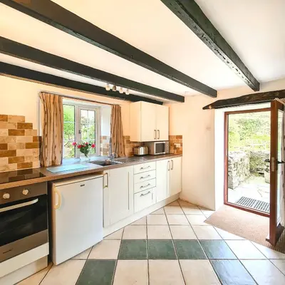 a kitchen with white cabinets and a large window at Ta Mill Cottages & Lodges - Pump Cottage in Launceston