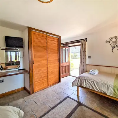 a bedroom with a bed and a sliding door at Ta Mill Cottages & Lodges - Dairy Cottage in Launceston
