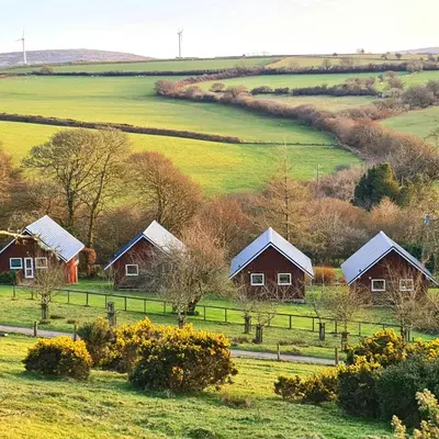 a group of cottages in a green field at Ta Mill Cottages & Lodges - Dairy Cottage in Launceston