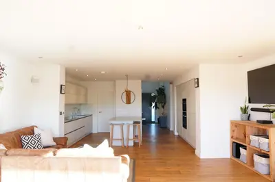 a living room with a couch and a kitchen at Stunning 4 Bedroom Home with Wild Spa, Gym & Hot Tub in Newquay