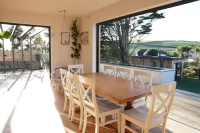 a dining room with a wooden table and chairs at Stunning 4 Bedroom Home with Wild Spa, Gym & Hot Tub in Newquay