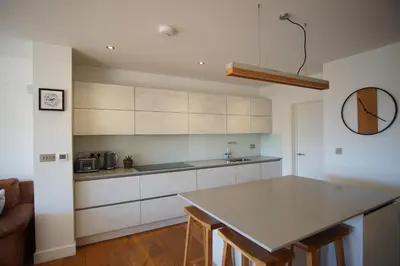 a kitchen with white cabinets and a counter top at Stunning 4 Bedroom Home with Wild Spa, Gym & Hot Tub in Newquay