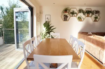 a dining room with a wooden table and white chairs at Stunning 4 Bedroom Home with Wild Spa, Gym & Hot Tub in Newquay