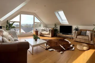 a living room with a couch and a table at Stunning 4 Bedroom Home with Wild Spa, Gym & Hot Tub in Newquay