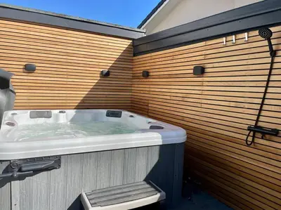 a large bath tub in a wooden wall at Stunning 4 Bedroom Home with Wild Spa, Gym & Hot Tub in Newquay