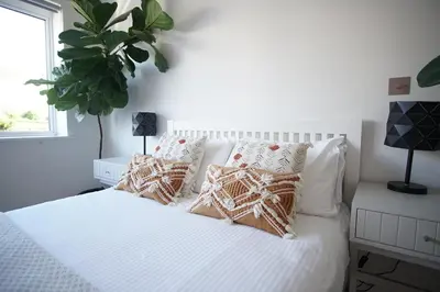 a bedroom with a white bed with pillows and a plant at Stunning 4 Bedroom Home with Wild Spa, Gym & Hot Tub in Newquay