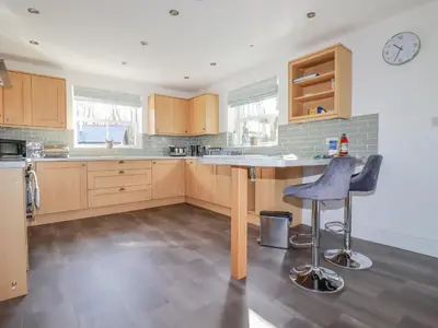 a kitchen with wooden cabinets and a table and chairs at Ilgram in Newquay