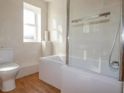 a white bathroom with a tub and a toilet at Ilgram in Newquay