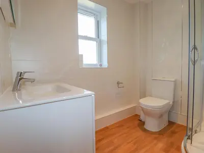 a white bathroom with a sink and a toilet at Ilgram in Newquay