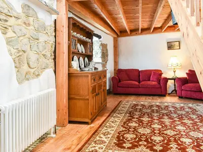 a living room with two red chairs and a stone wall at The Old Barn in Saint Day