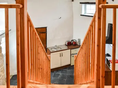 a kitchen with a wooden staircase with a sink and a counter at The Old Barn in Saint Day
