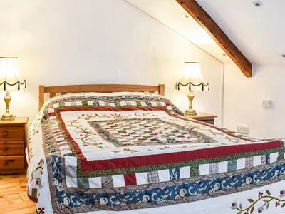 a bedroom with a bed with a quilt on it at The Old Barn in Saint Day