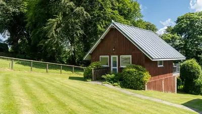 a small red barn with a grass yard at Ta Mill Cottages & Lodges - Meadowview Chalet 4 in Launceston