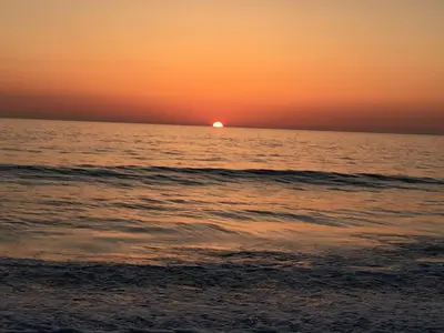 a sunset over the ocean with the sun in the distance at Shepherds hut with valley views in Bodmin