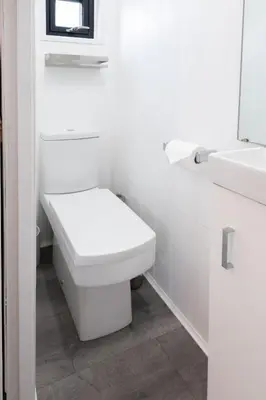 a white bathroom with a toilet and two sinks at Shepherds hut with valley views in Bodmin