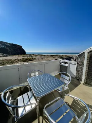 a table and chairs on a balcony with the ocean at Whispering Waves in Porthtowan, Beachfront Apartment in Porthtowan