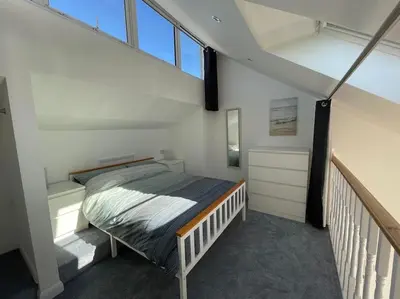 a bedroom with a bed in the middle of a loft at Whispering Waves in Porthtowan, Beachfront Apartment in Porthtowan