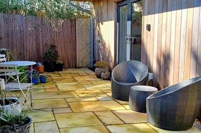 a patio with chairs and potted plants and a fence at Stylish coastal retreat in St Ives with parking in St Ives