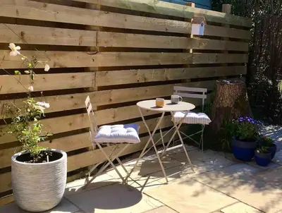 a table and chairs in front of a wooden wall at Stylish coastal retreat in St Ives with parking in St Ives