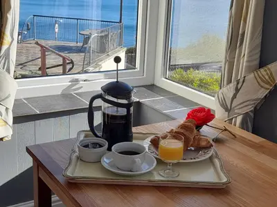 a breakfast tray with coffee and croissants on a table with a window at Eddystone Light Apartment in Mevagissey