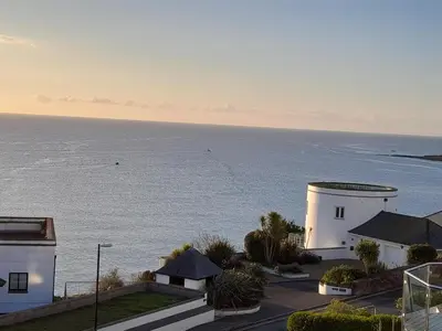 a white building with the ocean in the background at Eddystone Light Apartment in Mevagissey
