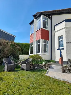 a house with two wicker chairs in the yard at Eddystone Light Apartment in Mevagissey