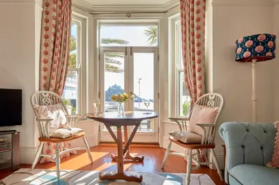 a living room with a table and chairs and a window at Ocean Villas in Marazion
